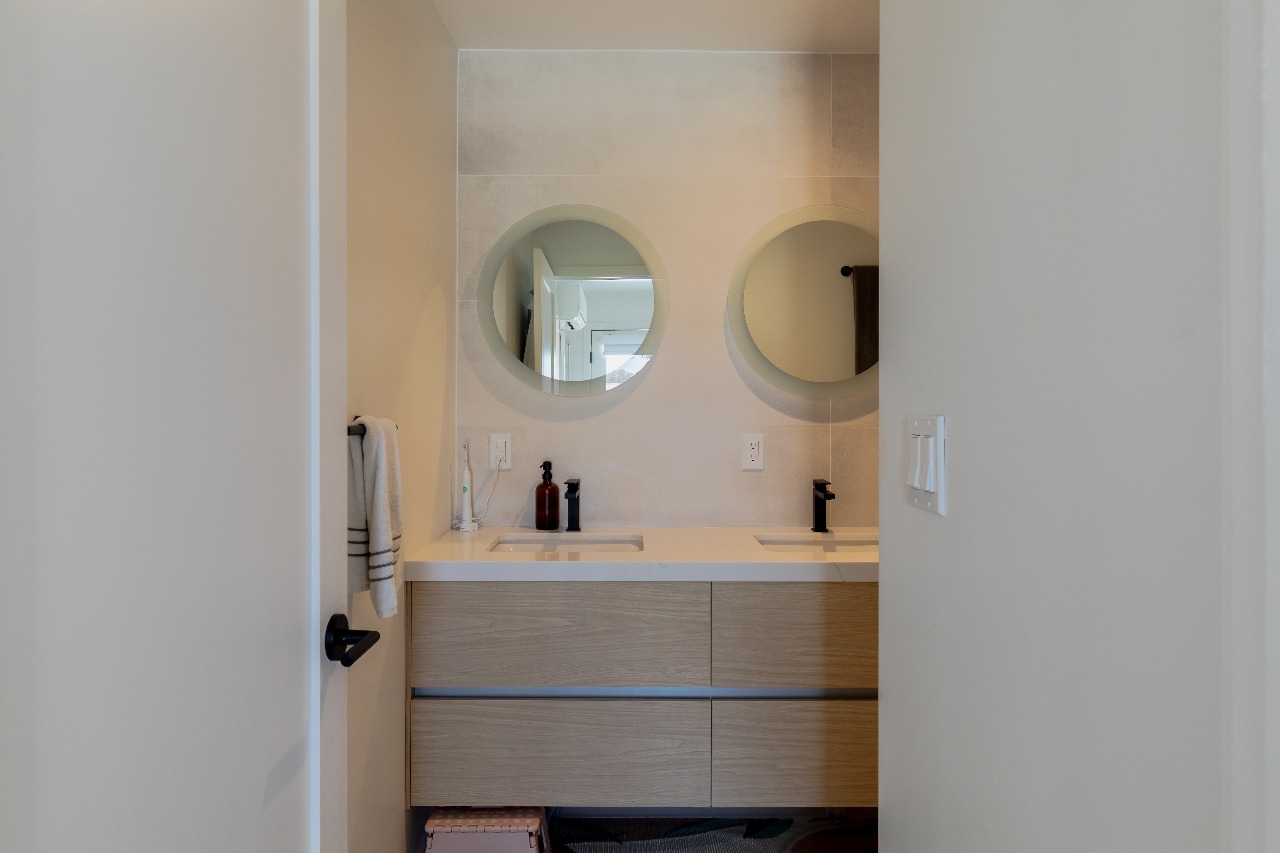 Bathroom with double round mirrors and white vanity in San Francisco full-house remodel