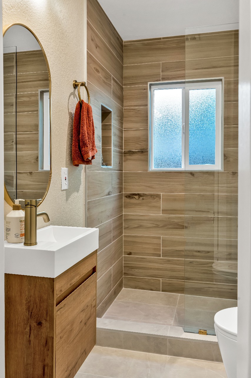 Bathroom with wood-look tile and gold faucet in Alameda full-house remodel